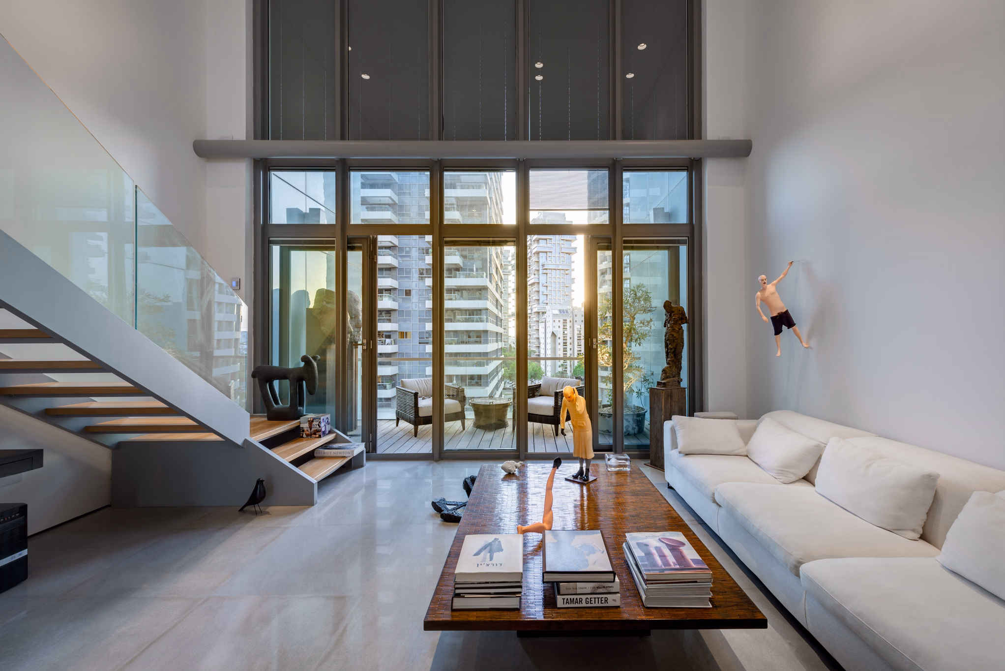 NAM Tower duplex living room with open staircase, white sofa and balcony view in Tel Aviv