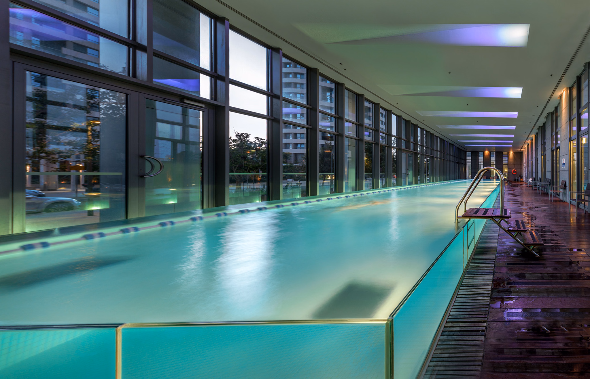Long indoor swimming pool with colored ceiling lights at NAM Tower in Tel Aviv